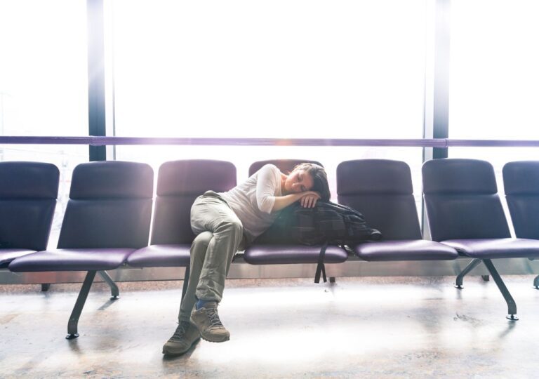Kobieta z jet lag śpi na krzesłach w lotniskowej poczekalni