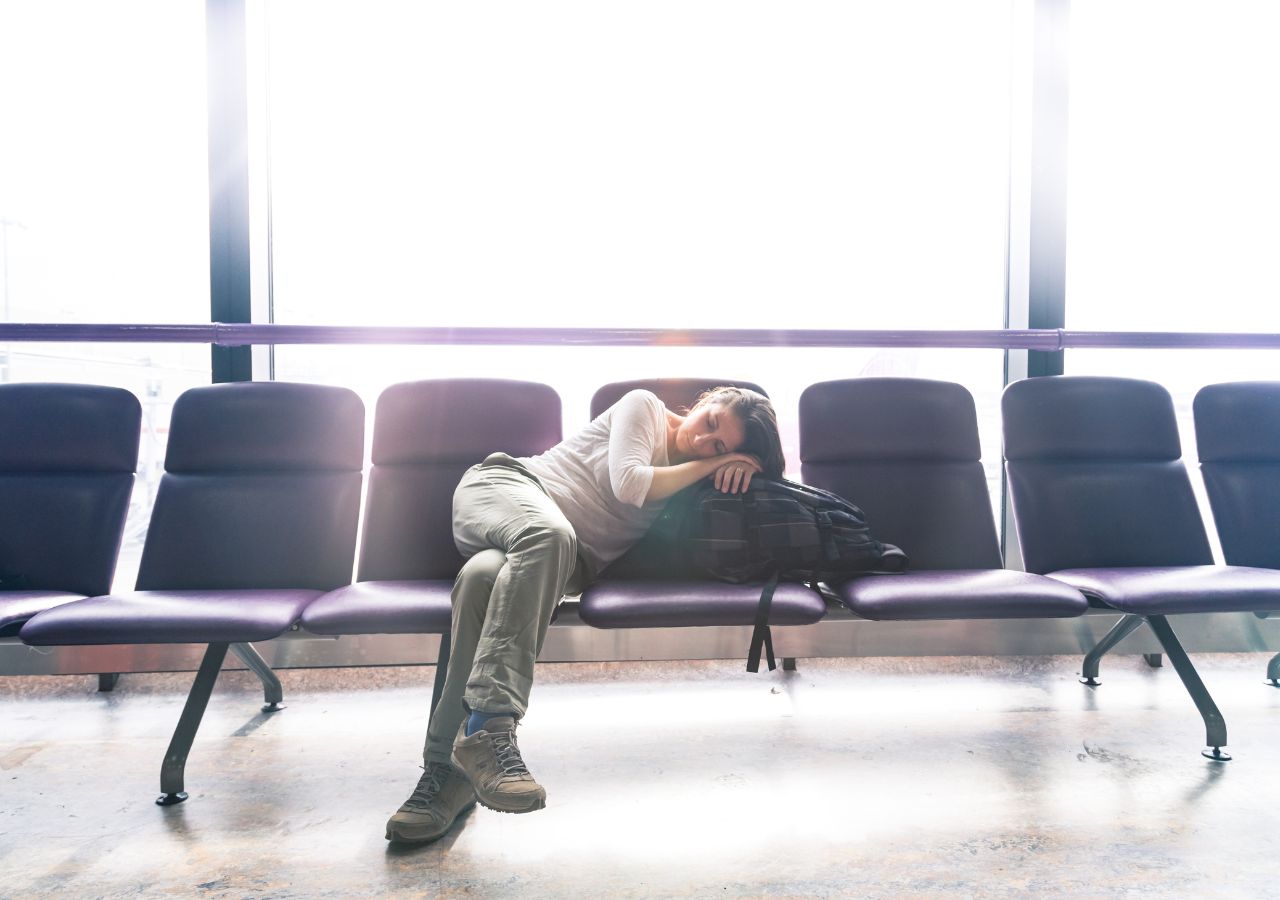 Kobieta z jet lag śpi na krzesłach w lotniskowej poczekalni
