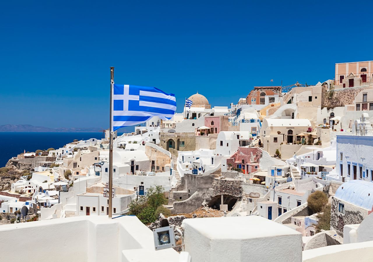 Grecka flaga na tle bialego greckiego miasteczka