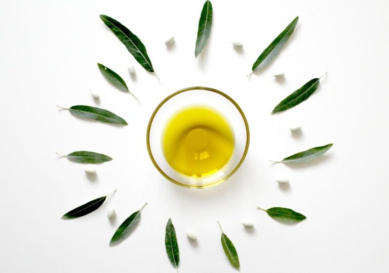 Oliwa z oliwek w miseczce w otoczeniu liści oliwki