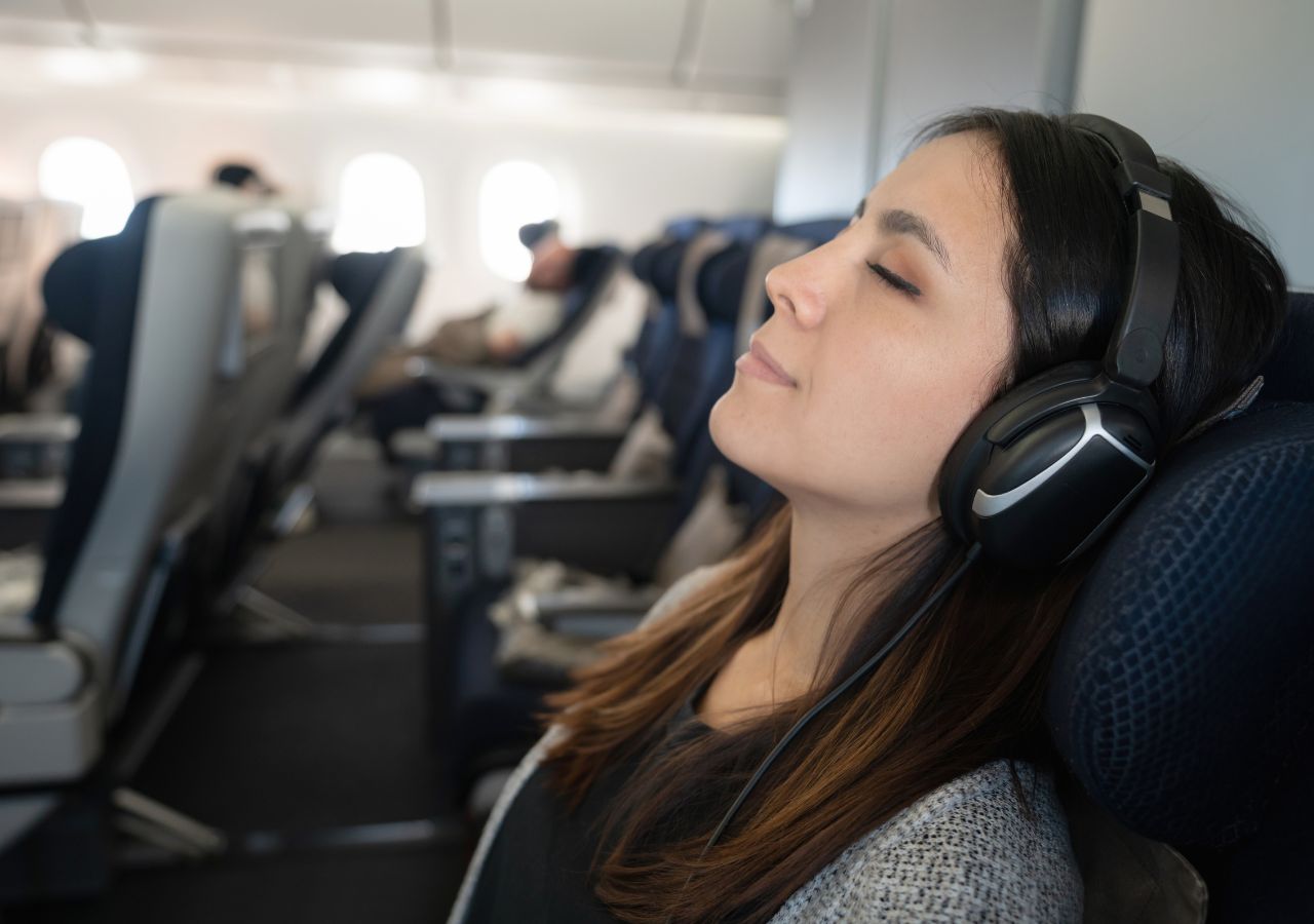 W samolocie zadowolona pasażerka śpi ze słuchawkami na uszach