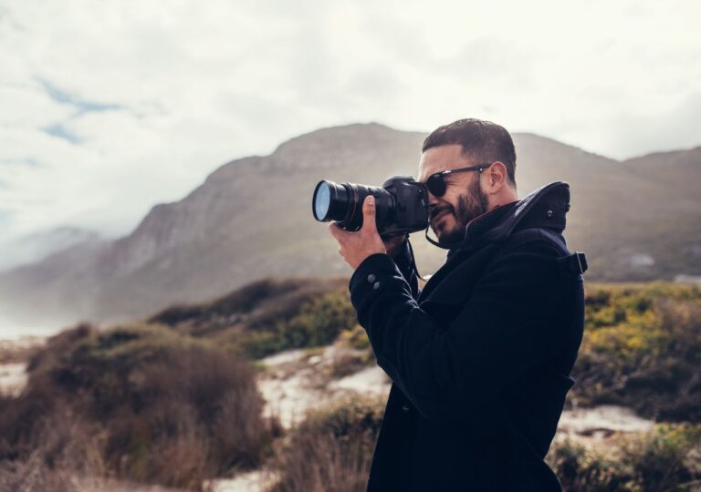 Mężczyzna z profesjonalnym aparatem fotograficznym wykonuje zdjęcie górskie