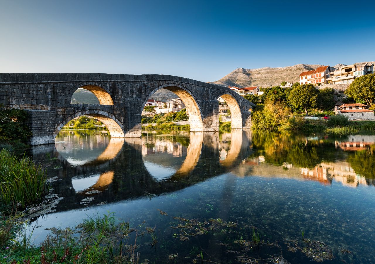 Most Arslanagića w Trebinje w bośni i hercegowinie - z odbiciem w wodzie i widokiem na miasto