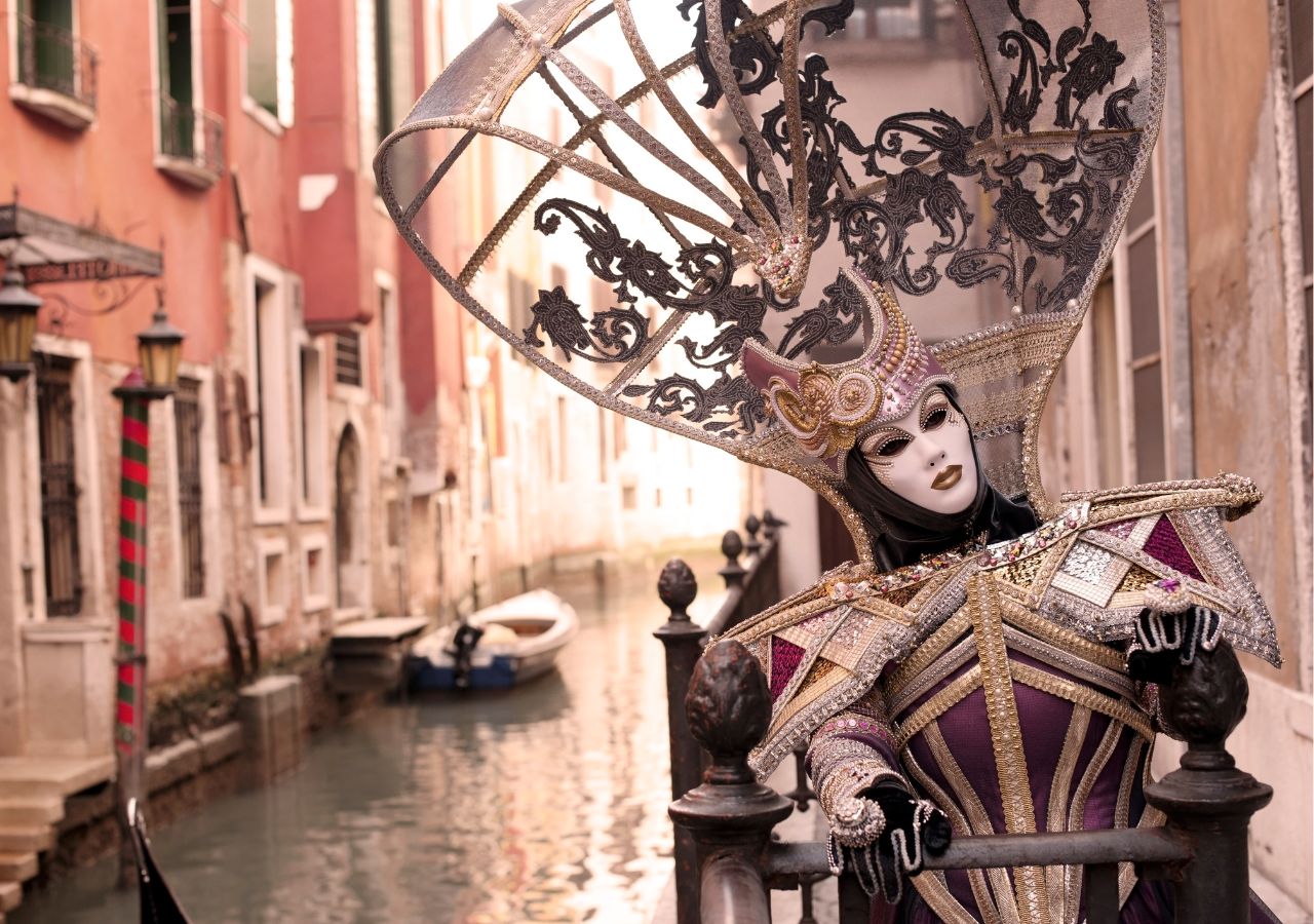 Uczestnik karnawału w Wenecji na kanałem w tradycyjnej masce i stroju