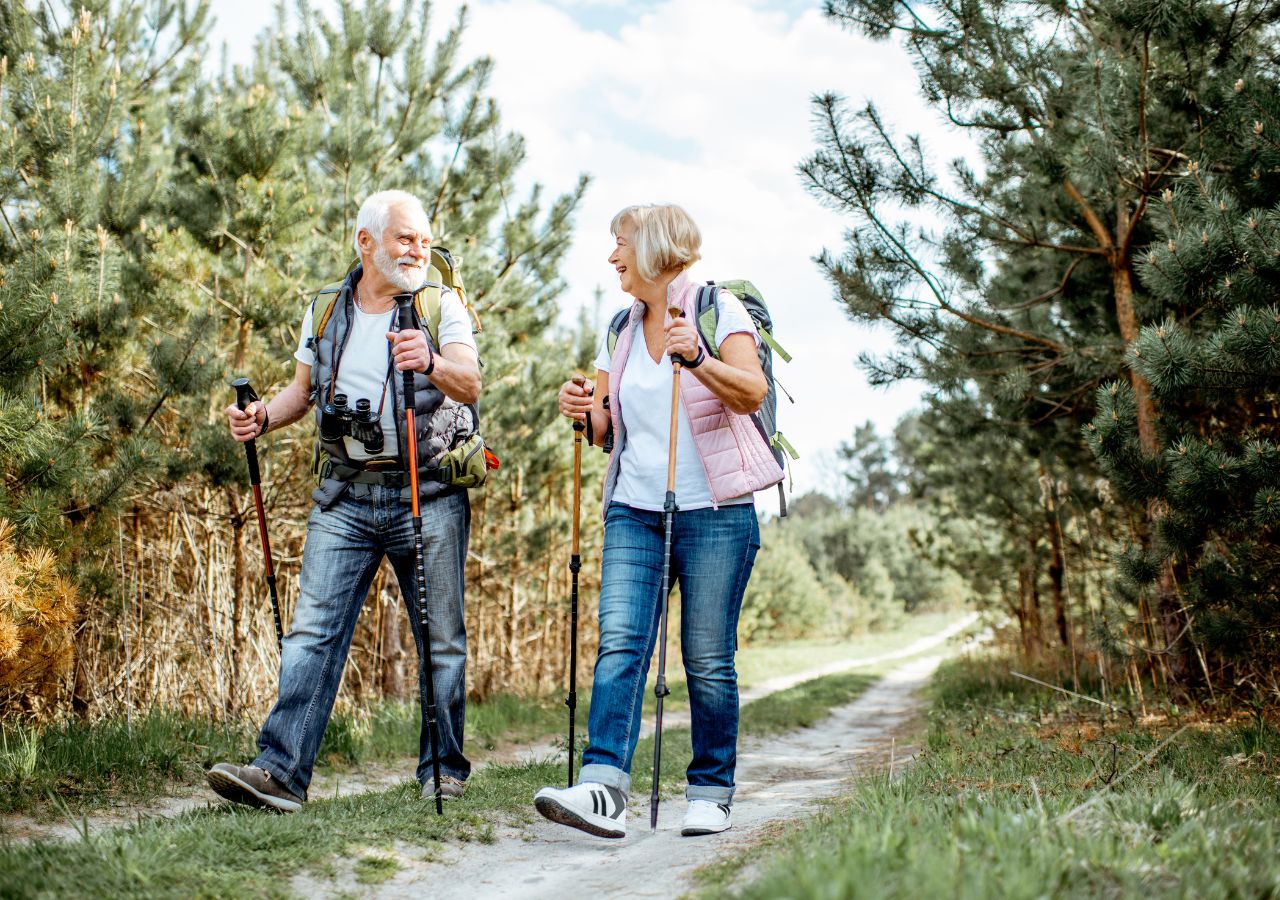 Para seniorów spaceruje z kijkami w lesie