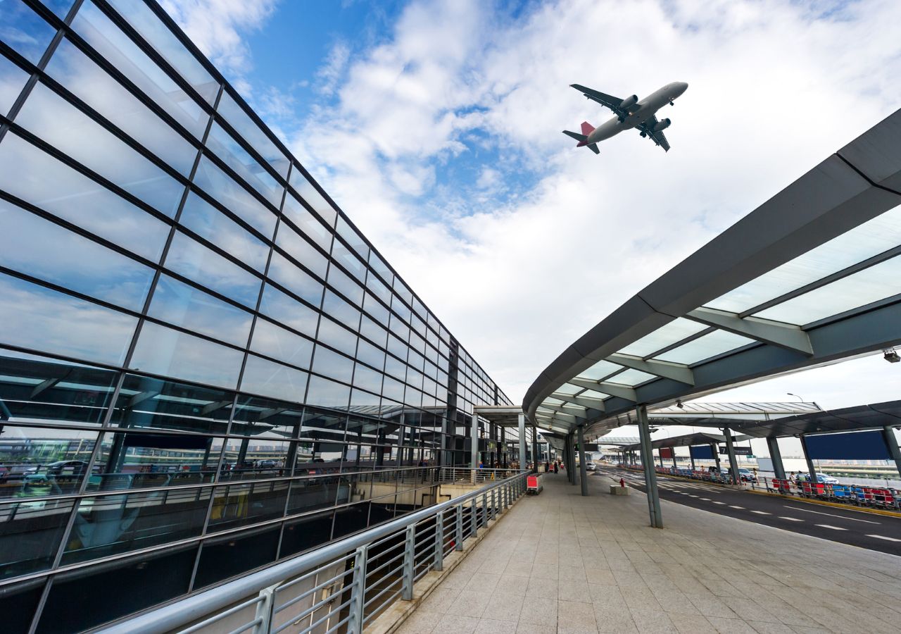 Samolot na niebie pomiędzy zabudowaniami lotniska