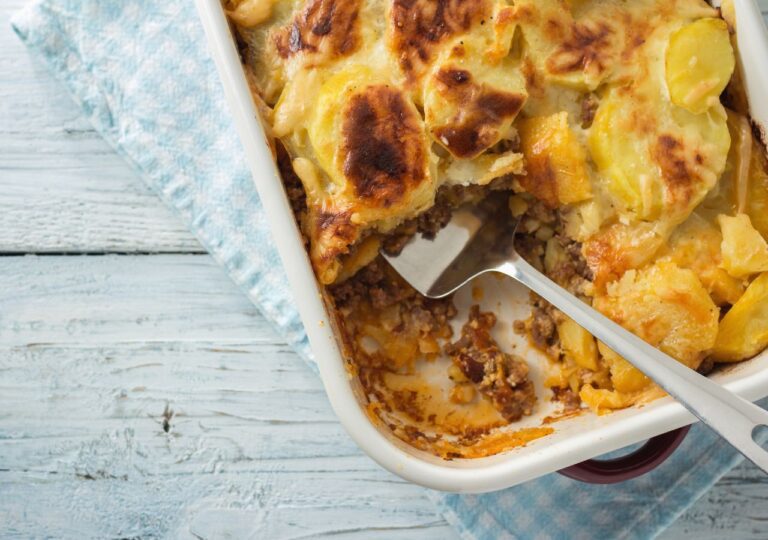 Moussaka w białym naczyniu żaroodpornym z wbitym widelcem