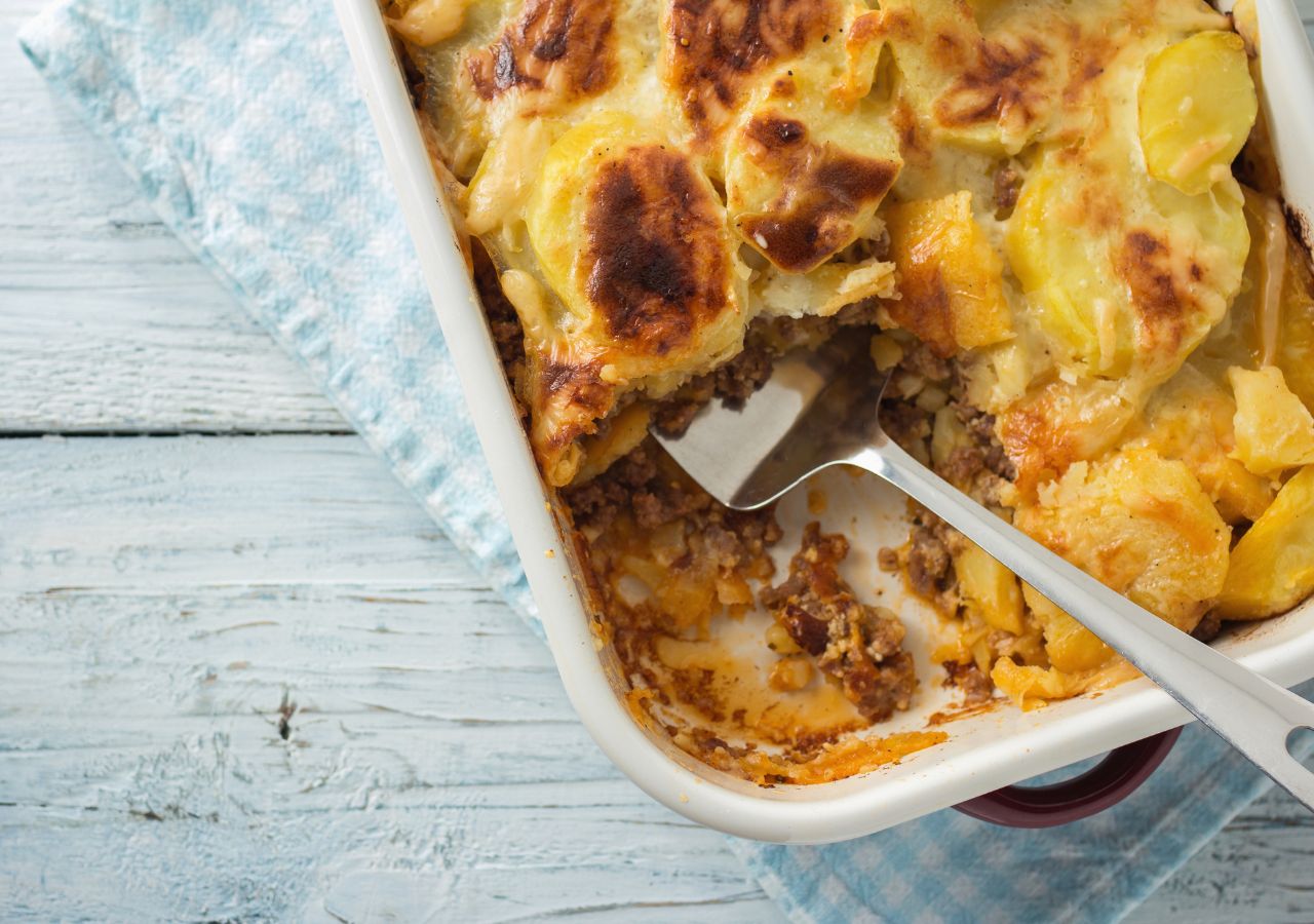 Moussaka w białym naczyniu żaroodpornym z wbitym widelcem