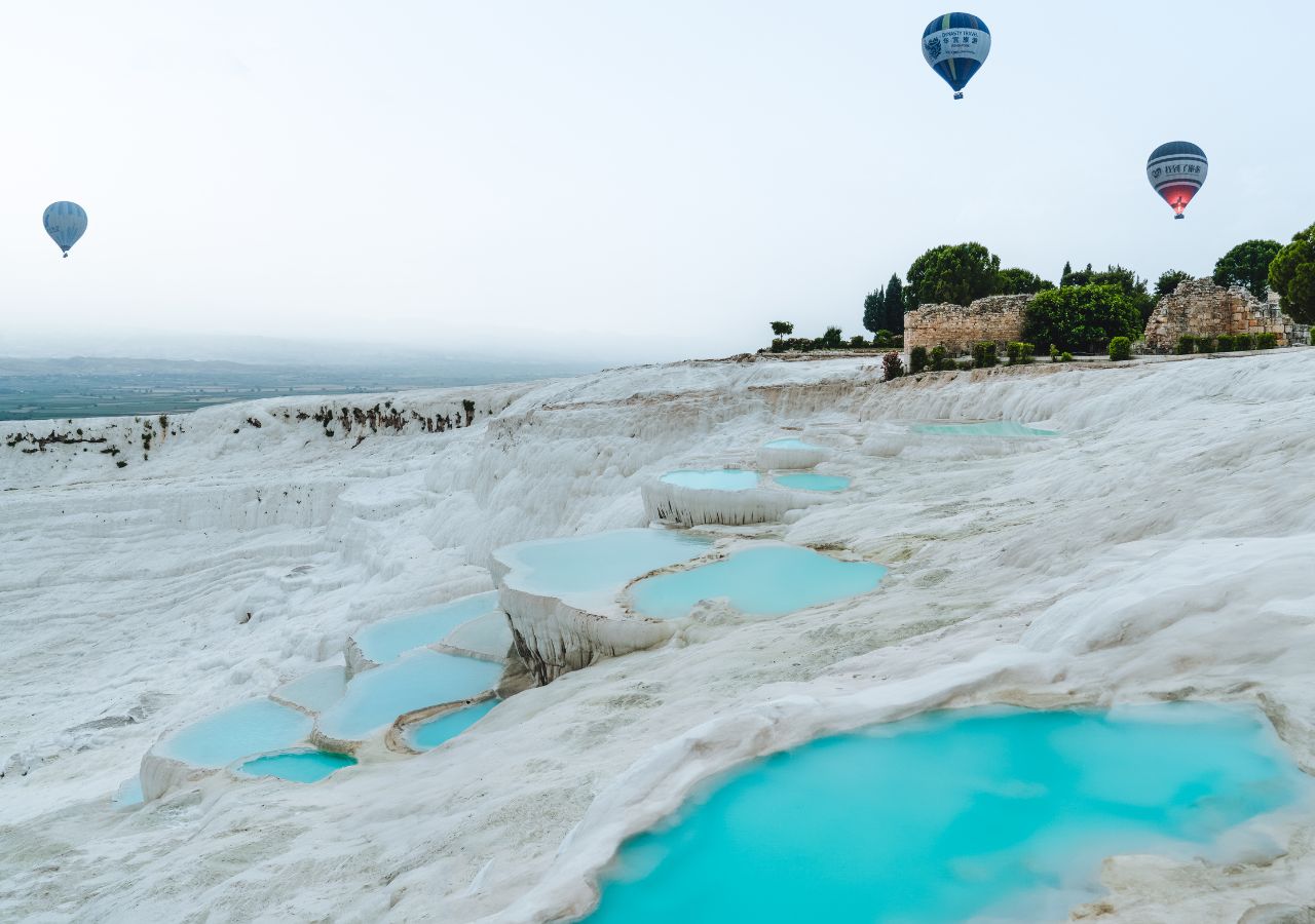 Baseny termalne w Pamukkale w Turcji z balonami w tle