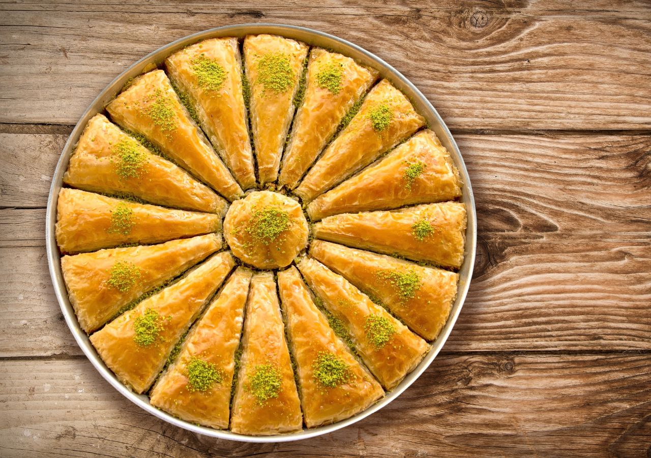 Okrągłą turecka baklawa pokrojona na mniejsze trójkątne kawałki