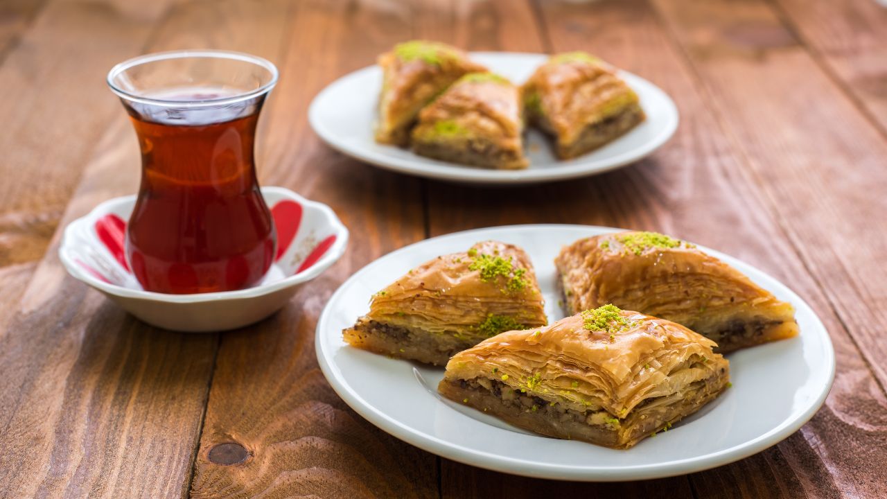 Herbata w tureckiej szklaneczce obok talerzyków z baklawą