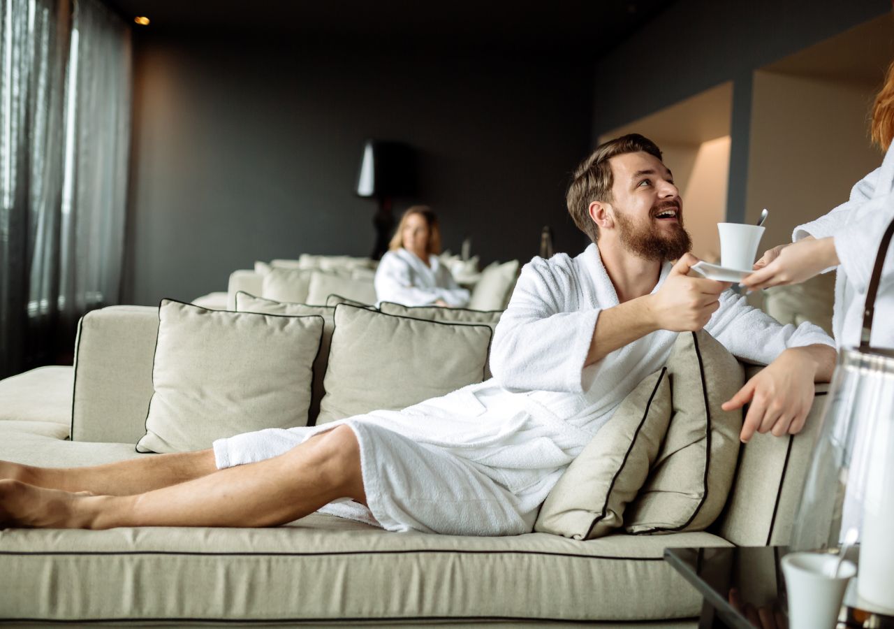 Mężczyzna na leżaku w hotelowym spa przyjmuje filiżankę napoju