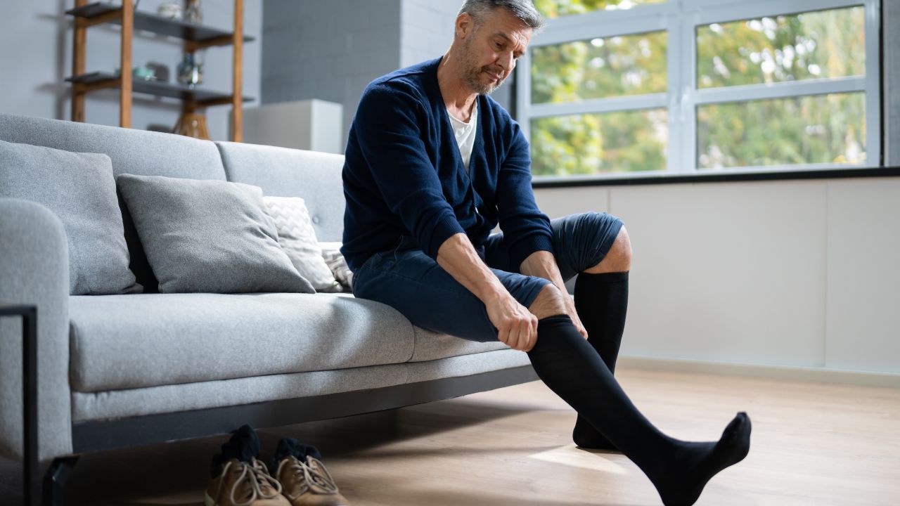 Mężczyzna ubiera skarpety kompresyjne