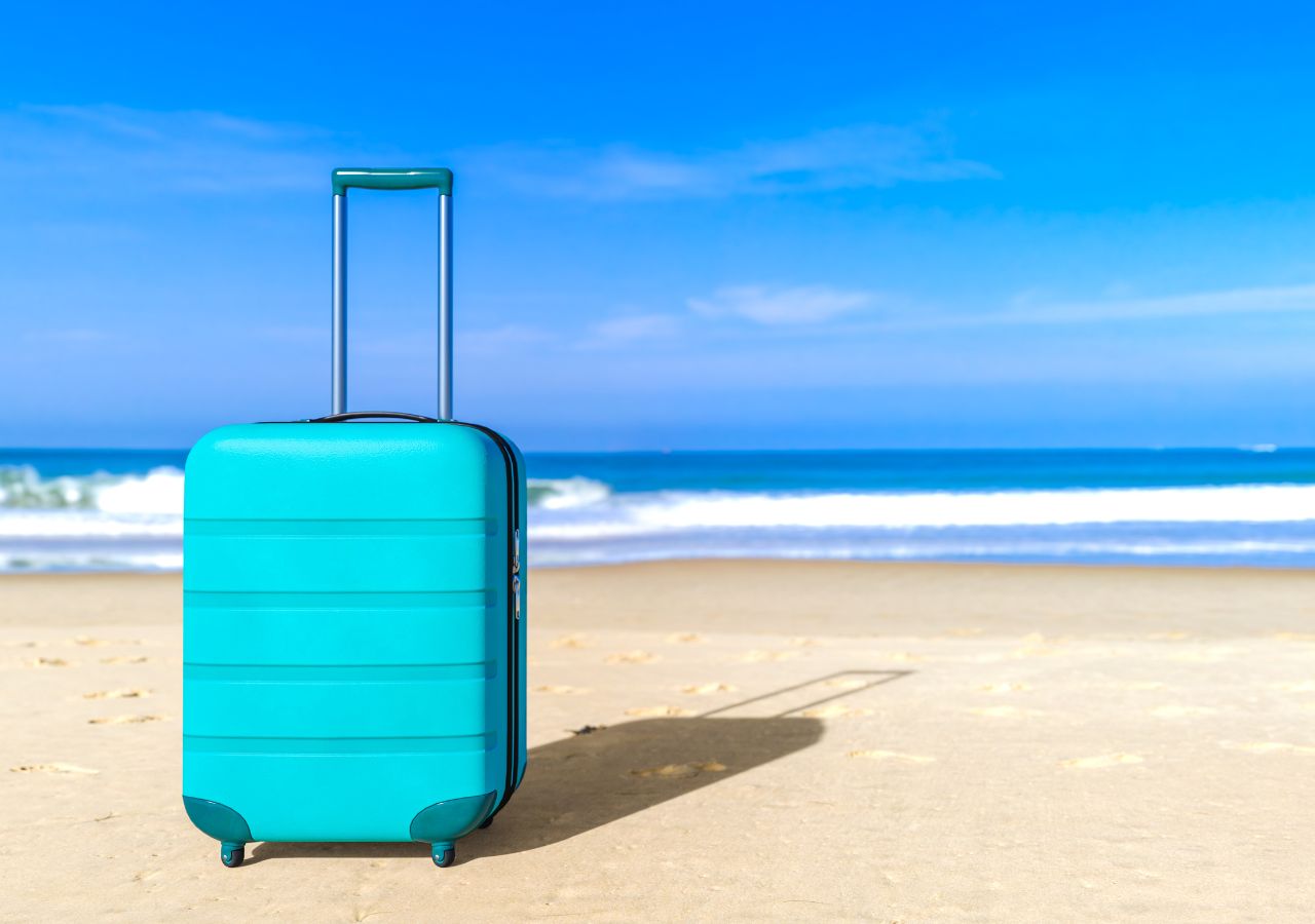 Niebieska walizka na piaszczystej plaży