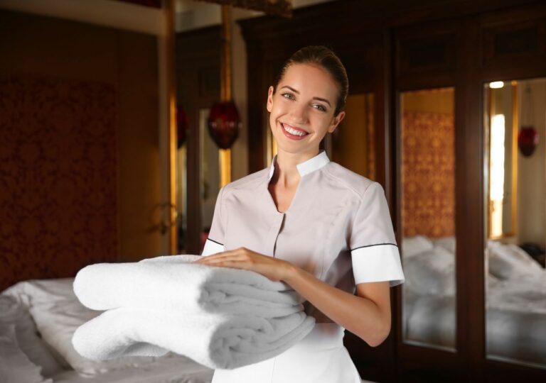 Pokojówka hotelowa rozkłąda w pokoju hotelowym czyste ręczniki