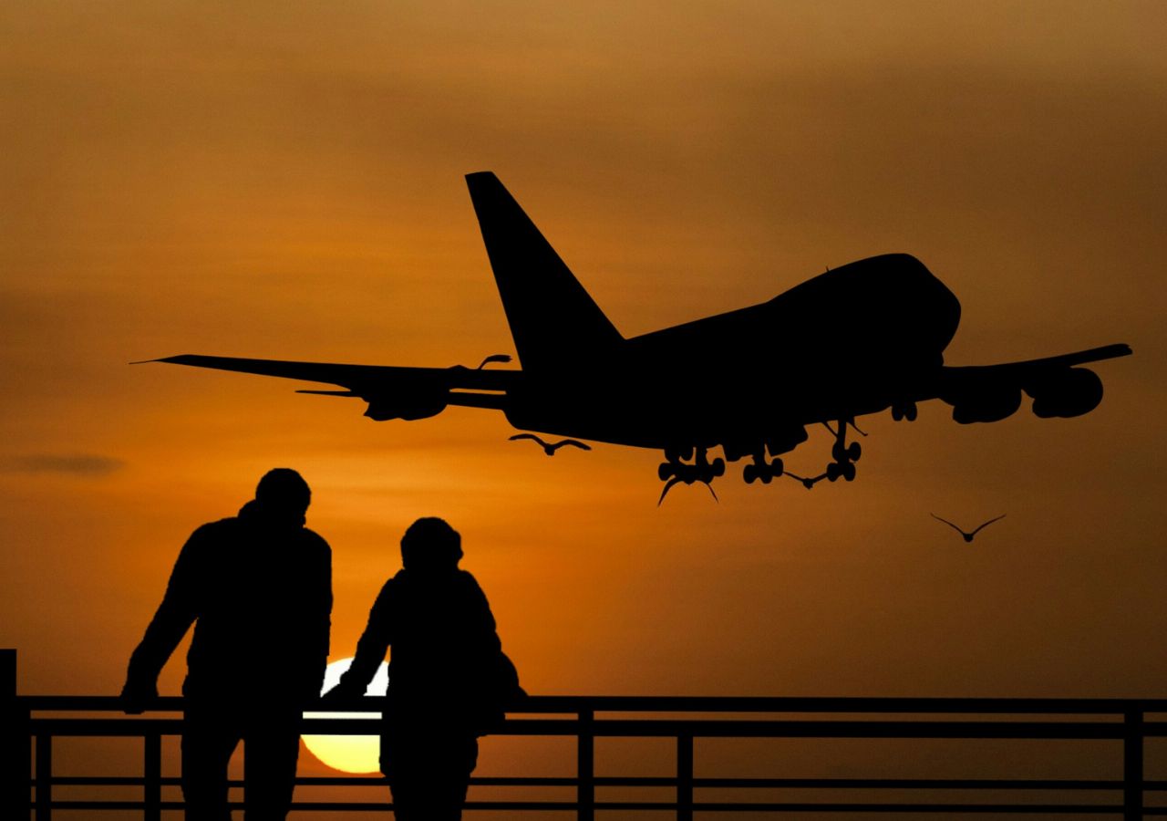 Samolot i para podróżnych na tle zachodzącego słońca